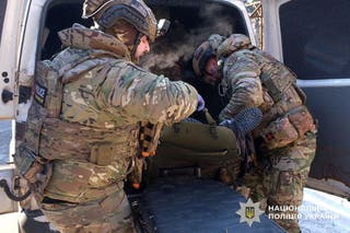 Ukrajinski policajci nose ozlijeđenog civila nakon ruskog udara u gradu Družkivka u Donjeckoj oblasti